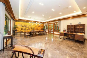Un hall de hotel espacioso con un mural tradicional chino, un instrumento de cuerda y un mostrador de recepción.