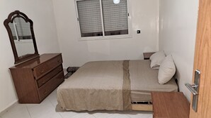 Een slaapkamer met een bed, een kaptafel, een spiegel en een raam.