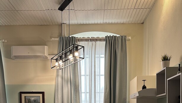 Una cocina compacta con lavadora, un comedor con mesa y sillas, y un ventanal con cortinas.