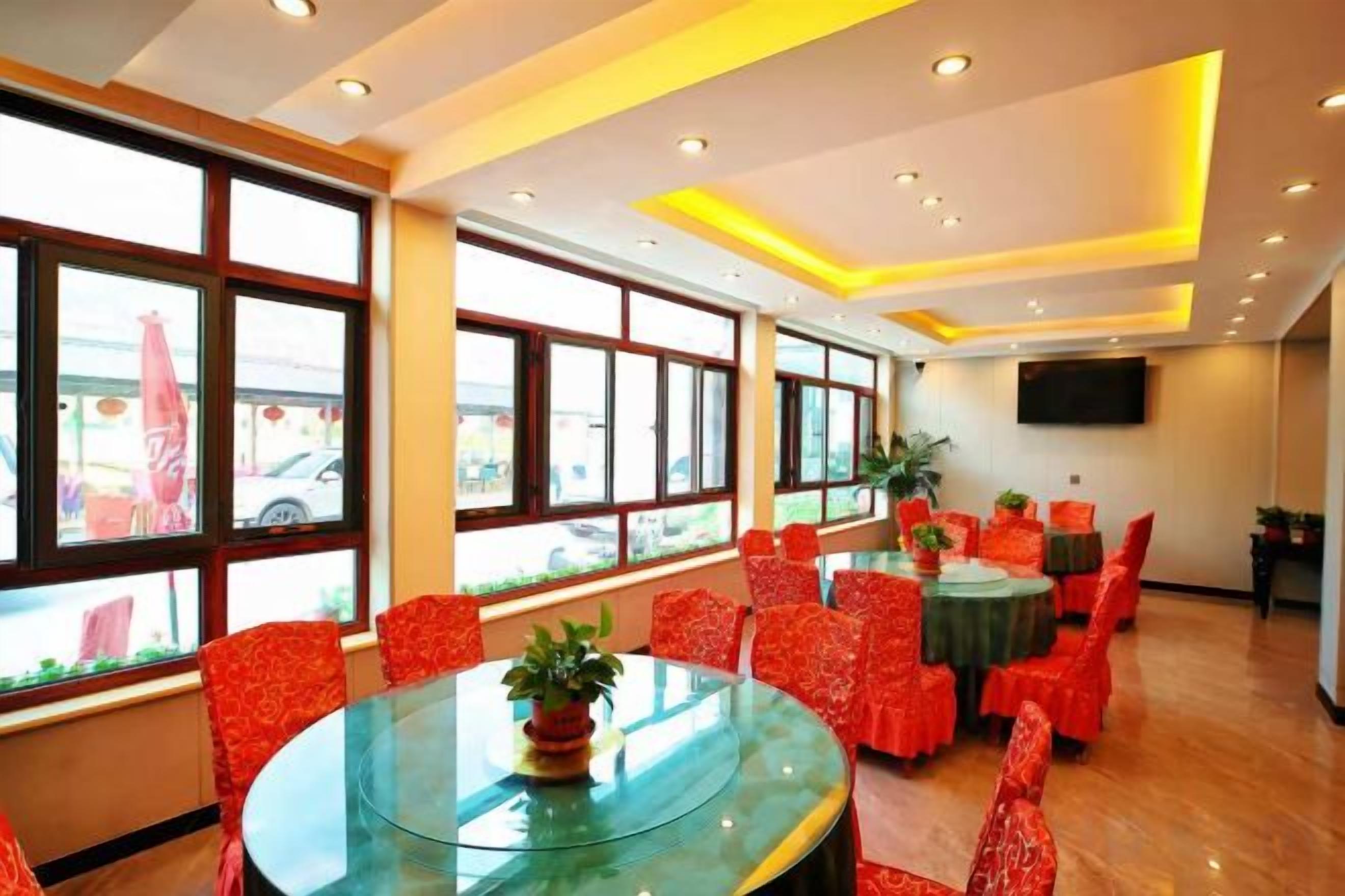 A dining area with round tables, red chairs, and large windows.