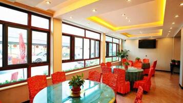 A dining area with round tables, red chairs, and large windows.