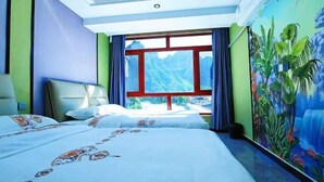 Hotelkamer met twee bedden, een groot raam en een muurschildering van een waterval.