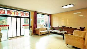 Un hall de hotel con mostrador de recepción, sofás, una mesa de centro y un ventanal grande.