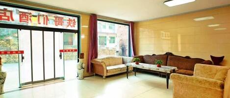 A hotel lobby with a reception desk, sofas, a coffee table, and a large window.