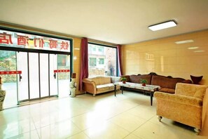 A hotel lobby with a reception desk, sofas, a coffee table, and a large window. - Tiegemen Express Hotel (Laishui)