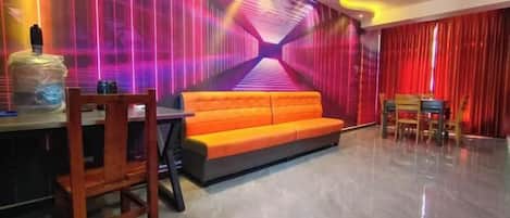 A modern interior with a sofa, dining table, chairs, and a wall with a geometric light design.