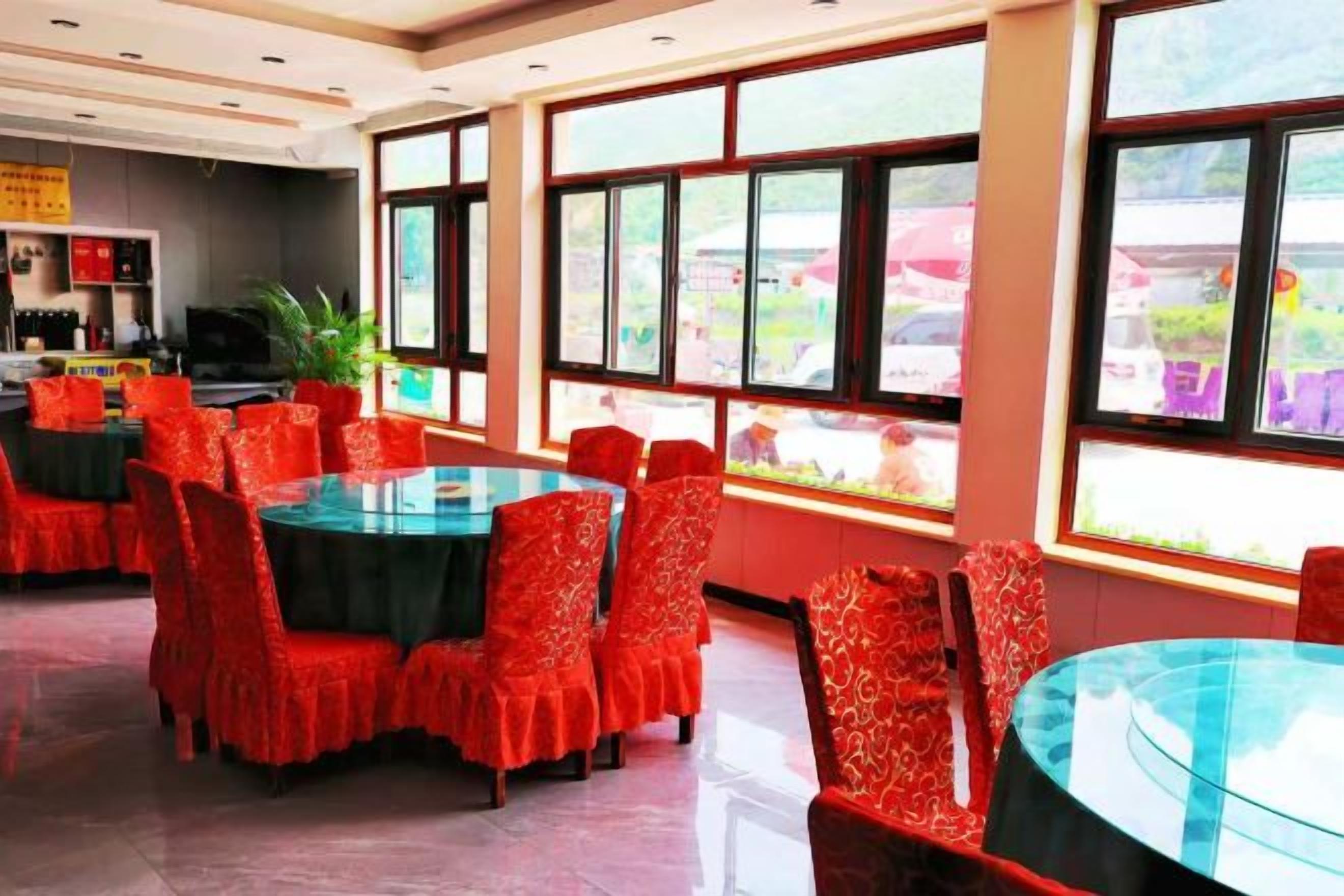 A restaurant with round tables and chairs, large windows, and a view of the outside.