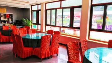 A restaurant with round tables and chairs, large windows, and a view of the outside.