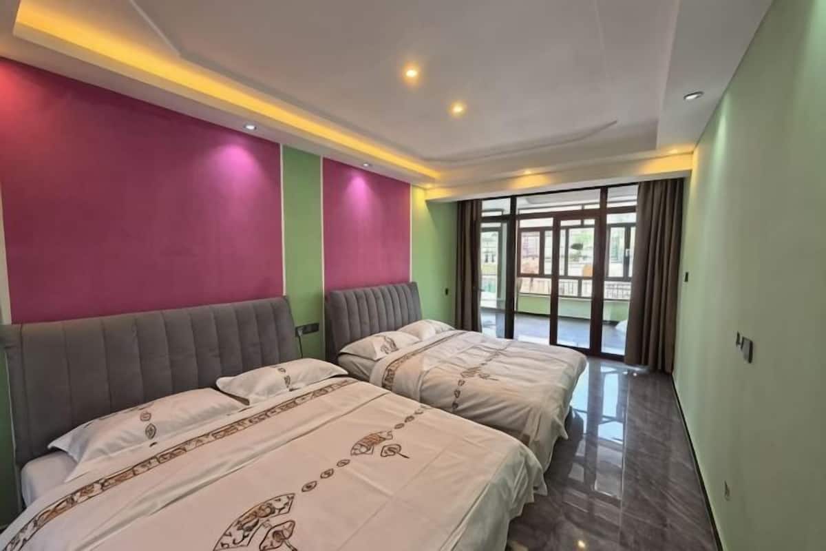 A hotel room with two beds, a balcony, and a view of the outdoors.
