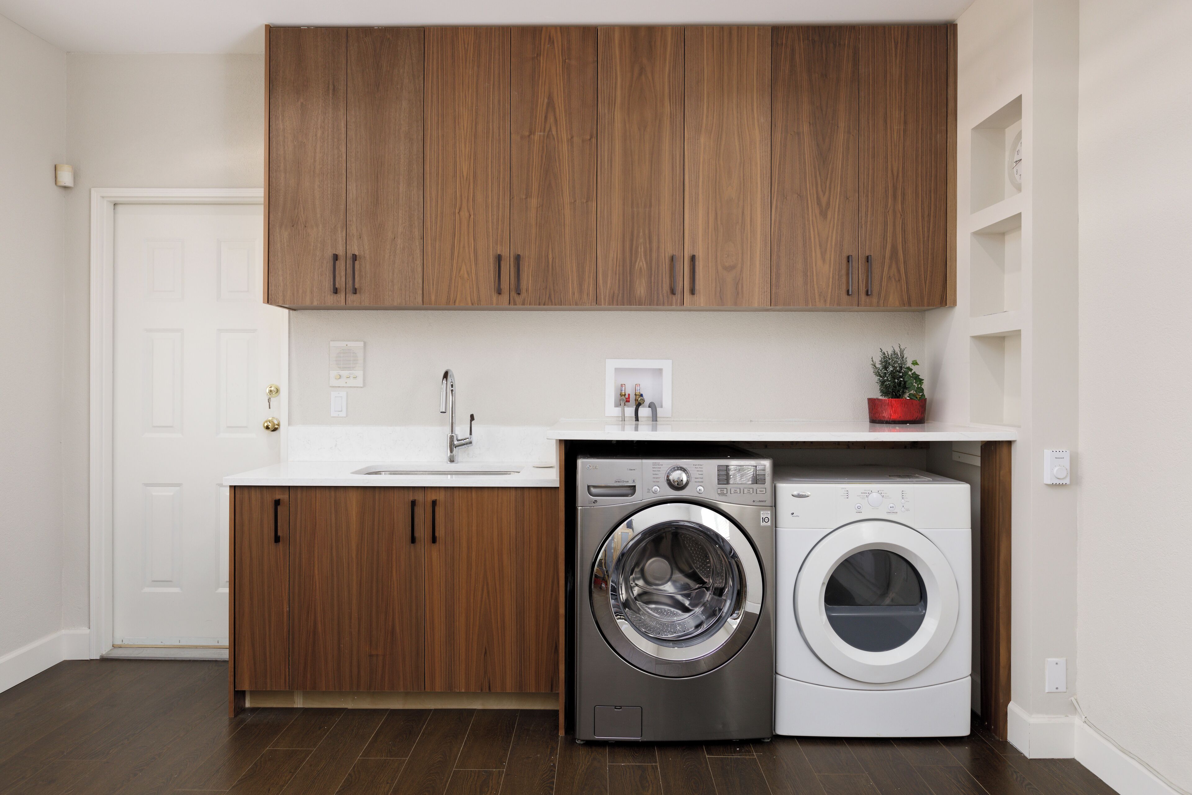 A modern laundry room with wooden cabinets, a washing machine, and a dryer.