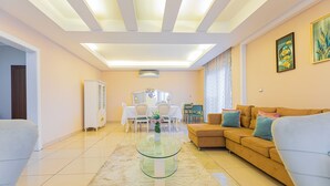 Un salón amplio con una mesa de centro de cristal, un sofá y un comedor con mesa y sillas.