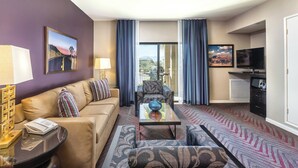 A hotel room with a sofa, armchair, coffee table, TV, and a balcony with curtains. - Indio Resort Condos by WorldMark (Indio)