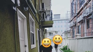A narrow alleyway between buildings with a green wall on one side and a white wall on the other. There are air conditioning units on the walls and a person walking down the alley. - Quiet and spacious 2-bedroom apartment with AC, WiFi in exciting Turkeyen (Turkeyen)