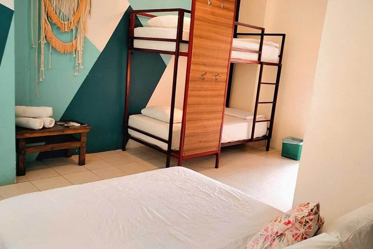 A room with a bunk bed, a small table with towels, and a wall with geometric patterns.