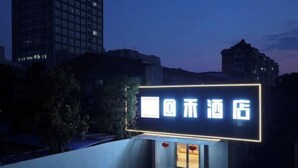 Une enseigne d’hôtel avec des lettres lumineuses, une entrée moderne et un espace de stationnement.