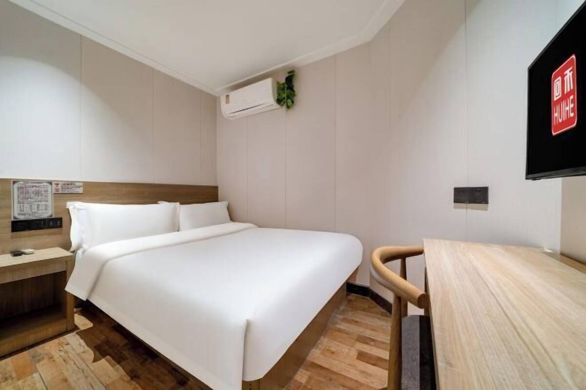 Una habitación de hotel con cama, escritorio, aire acondicionado y televisor.