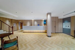 Un espace d’accueil comprenant un comptoir de réception, un escalier et un sol décoré de motifs en chevrons.