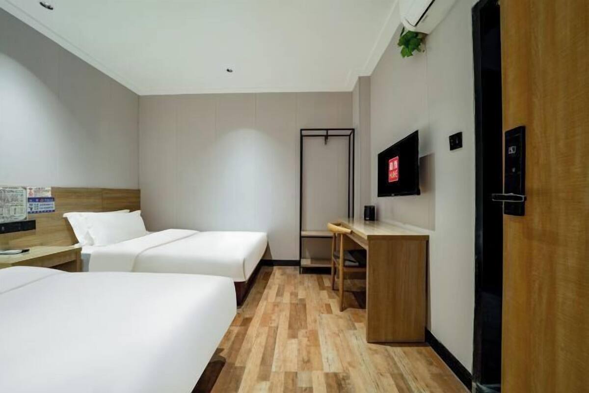 Habitación de hotel con dos camas, un escritorio, un televisor y un armario.