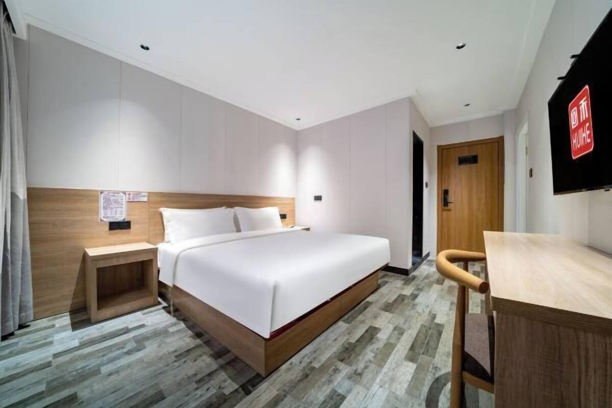 Una habitación de hotel con cama, mesita de noche, escritorio y televisor.