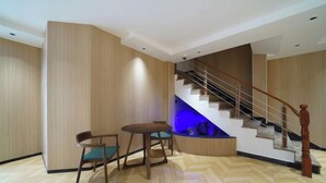 Un intérieur moderne avec un plancher en bois, un escalier doté d’une rampe en bois et un coin éclairé de lumière bleue.