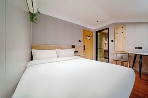 A modern hotel room with a large bed, a wooden headboard, a small table, and a mirror. - Huihe Hotel (Shanghai Wusongkou International Cruise Port Branch) (Shanghai)