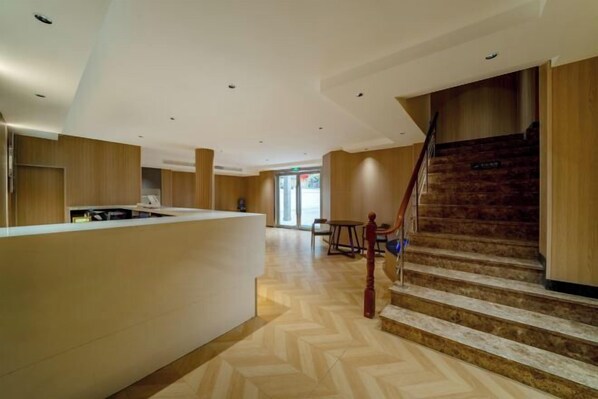 A modern hotel lobby with a reception desk, a staircase, and a dining area. - Huihe Hotel (Shanghai Wusongkou International Cruise Port Branch) (Shanghai)