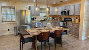 A modern kitchen with wooden cabinets, stainless steel appliances, and a dining area with a wooden table and chairs.