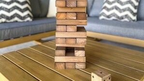 A wooden block tower on a table with a dice beside it.