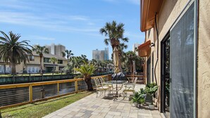 A patio with outdoor seating, a pool, and palm trees.