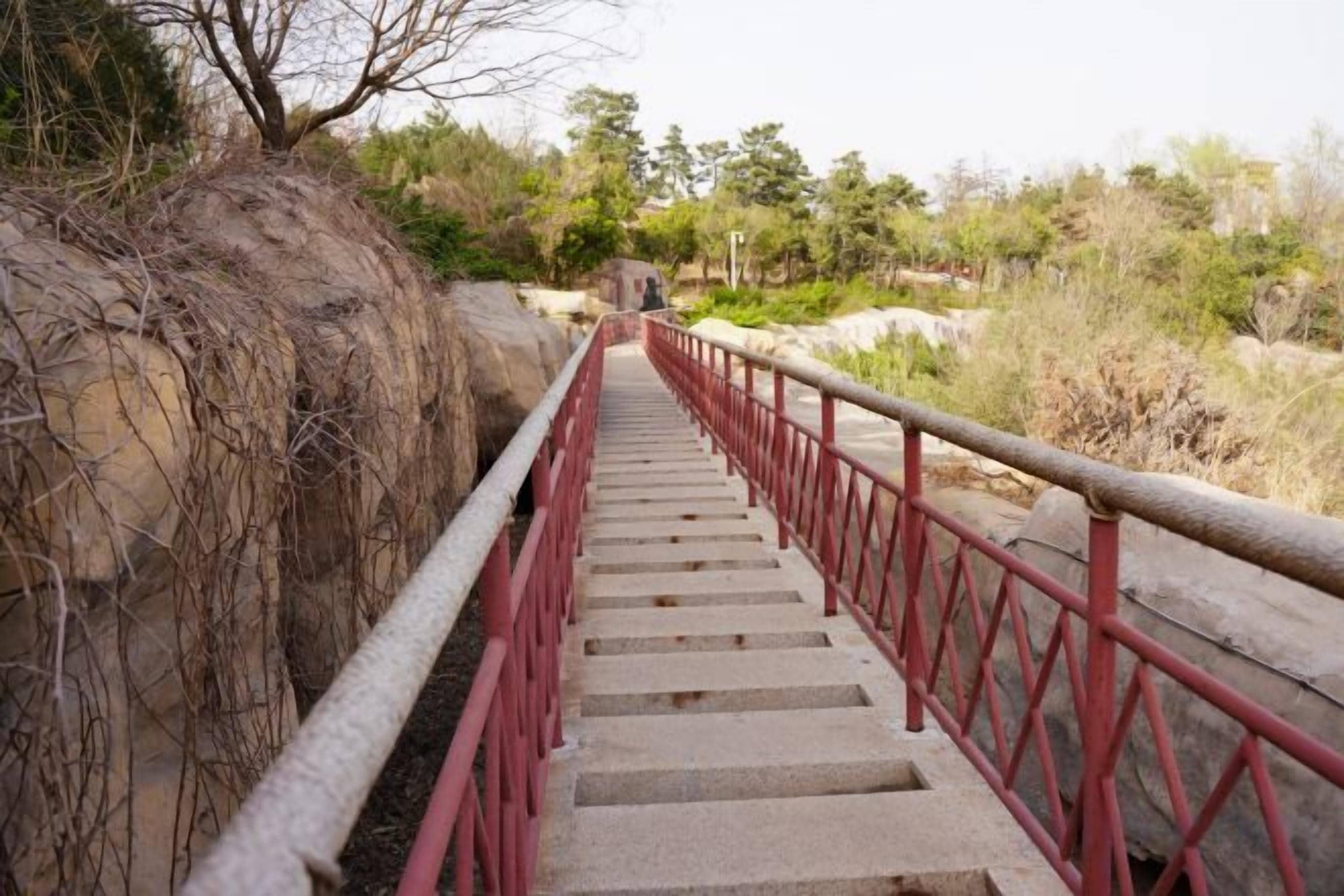 A concrete staircase with red railings leading to a higher level.