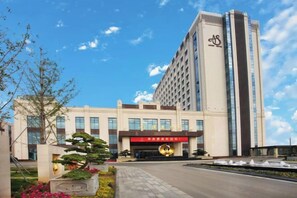 Un hotel con una fachada moderna, una entrada destacada y un jardín bien cuidado.