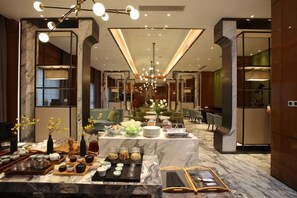 Un hall d’hôtel moderne avec un comptoir d’accueil en marbre, un espace salon et un lustre.