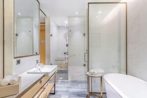 Une salle de bain moderne avec une douche à parois de verre, un meuble-lavabo avec un miroir et une baignoire.