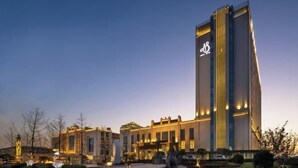 Un hotel moderno con una torre vertical destacada y una entrada bien iluminada.