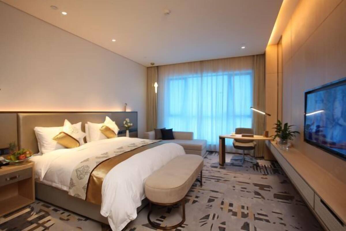 Une chambre d’hôtel moderne équipée d’un grand lit, d’un bureau, d’un canapé et d’une télévision.