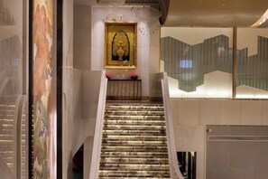 Un escalier muni d’une rampe menant à un espace d’accueil, au-dessus duquel est accrochée une œuvre d’art encadrée.