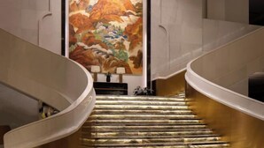Una escalera curva con detalles de mármol y un cuadro grande en la pared superior.