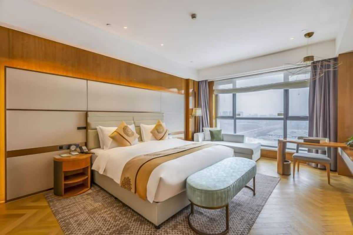 Une chambre d’hôtel moderne, dotée d’un grand lit, d’un bureau et offrant une vue sur la ville.