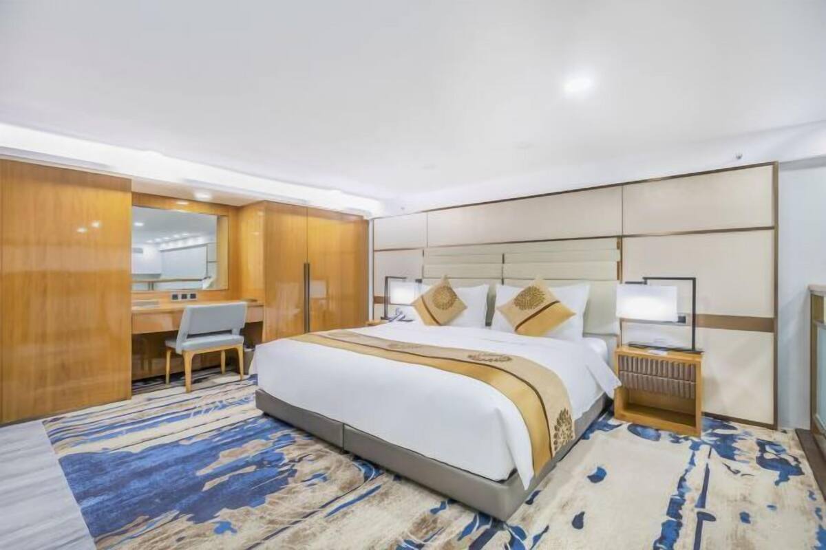 Une chambre d’hôtel avec un grand lit, un bureau et un miroir.