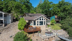 A house with a deck, a stone staircase, and a view of a river. - Lakeside Paradise! Private Dock w/ Hot Tub! (Jasper Township)