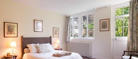 Een slaapkamer met een groot bed, twee bedlampen, een radiator en lijstwerken aan de muren.