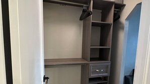 A walk-in closet with open shelves, a small drawer unit, and a ceiling light fixture. - Modern Escape (Loa)