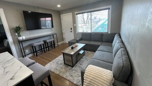 A modern living room with a grey sofa, a wooden coffee table, and a white rug. - Modern Escape (Loa)