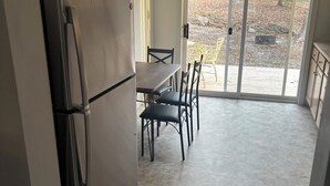 Eine kleine Küche mit Kühlschrank, einem Esstisch mit Stühlen und einer Glastür zu einer Terrasse.