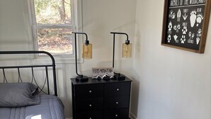 Ein Schlafzimmer mit einem Bett, einem Nachttisch, einer Wandlampe und einem gerahmten Bild von Waldbewohnern.