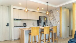 Een moderne keuken met houten kasten, een centraal kookeiland met barkrukken, een ingebouwde kookplaat en een koelkast.