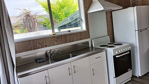 Eine kleine Küche mit Fenster, inklusive Herd, Spüle und Kühlschrank.