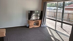 Ein Zimmer mit einer großen Schiebeglaswand, einer Holz-Unterhaltungseinrichtung mit Flachbildfernseher und einem grauen Teppich.