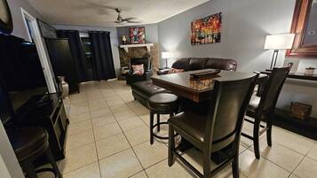 A dining area with a table and chairs, a sofa, a fireplace, and a television.
