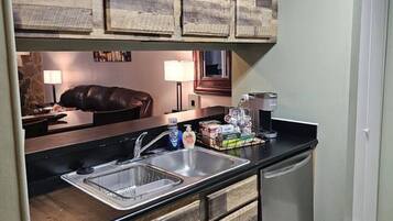 A compact kitchen with wooden cabinetry, a double sink, and a dishwasher.